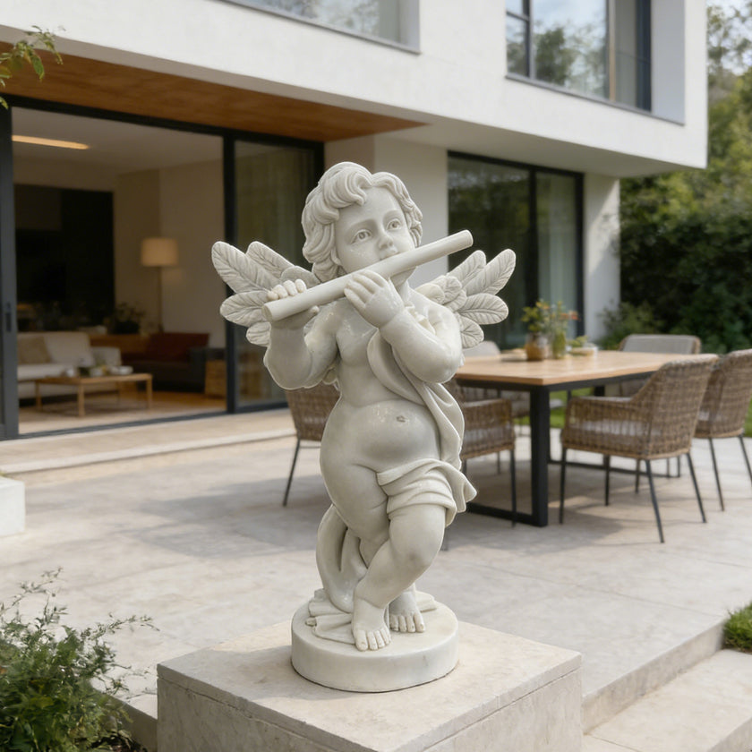 White marble cherub angel flute statue displayed on a modern patio, adding a soft classical touch to outdoor home decor.