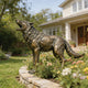 bronze howling wolf statue with an antique patina finish, positioned in a luxury estate landscaping.