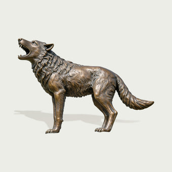 bronze howling wolf statue with an antique patina finish, positioned in a luxury estate landscaping.