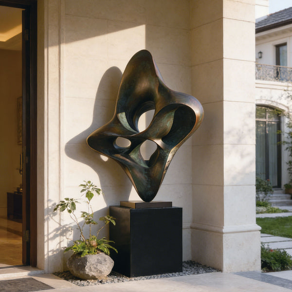 Abstract bronze large woven knot form sculpture on a pedestal in front of a modern building