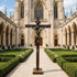 Statue of Christ on the Cross Bronze Sculpture centered in a formal garden courtyard leading up to a grand stone cathedral.