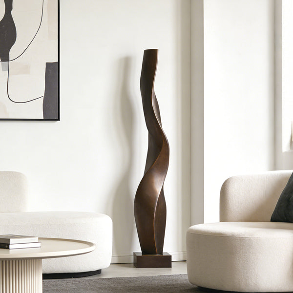 Elegant Twist Abstract Bronze Sculpture in a Modern living room with a decorative floor lamp between two white chairs.