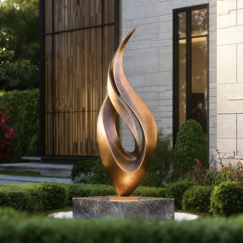 Abstract large dancing flame bronze sculpture in a garden setting with a building in the background