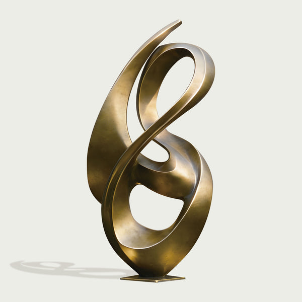 Abstract flowing gold bronze sculpture on a pedestal on a light gray background