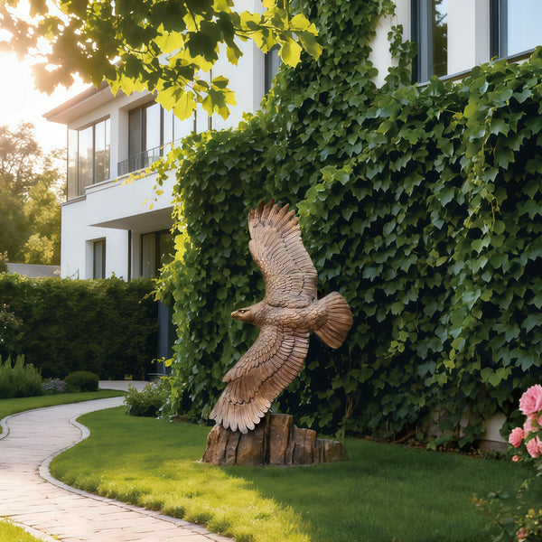 Wings of freedom eagle bronze sculpture in front of a building with greenery