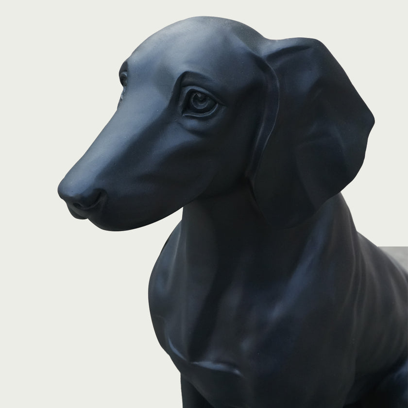 Black bronze dog statue on a light gray background