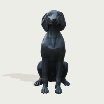 Black bronze dog statue on a light gray background