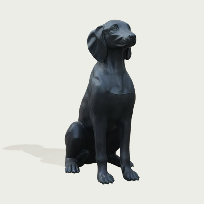 Black bronze dog statue on a light gray background