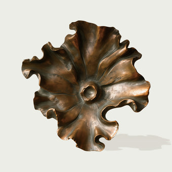 Bronze wall sculpture sunlit ripples floral form on a light gray background