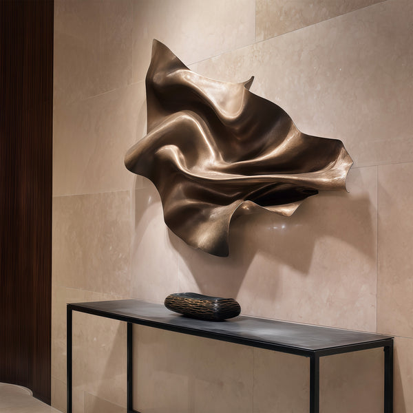 Floating Veil Bronze wall sculpture on a textured wall with a black console table below.