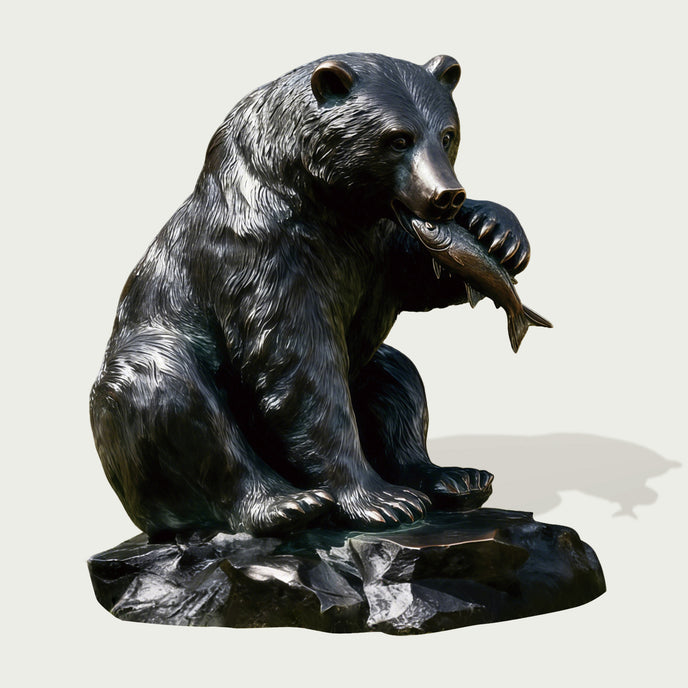 Bronze statue of a bear holding a fish on a white background