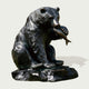Bronze statue of a bear holding a fish on a white background