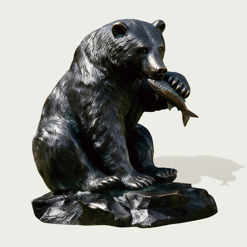 Bronze statue of a bear holding a fish on a white background