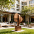 Contemporary Abstract  Bronze Geometric Sculpture Arcus Stamp chairs, and tables in front of a building.