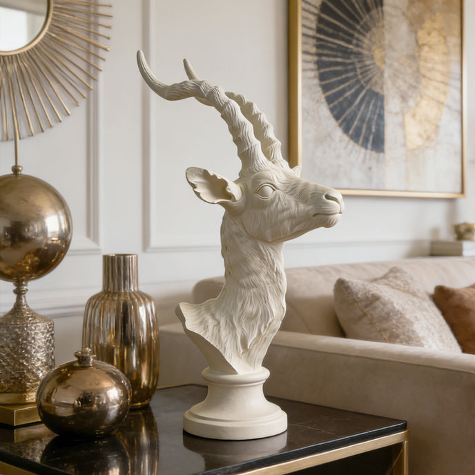 Graceful Antelope Profile Head Bust Bronze  on a table with gold vases and a couch in the background.