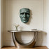 Dramatic Male Wall Art Bronze Sculpture on a wall above a modern console table with a vase and books.