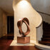 Intertwined Geometric Knot Abstract Bronze Statues on a square pedestal, displayed in a grand interior hallway with a curved staircase and cream-colored walls.