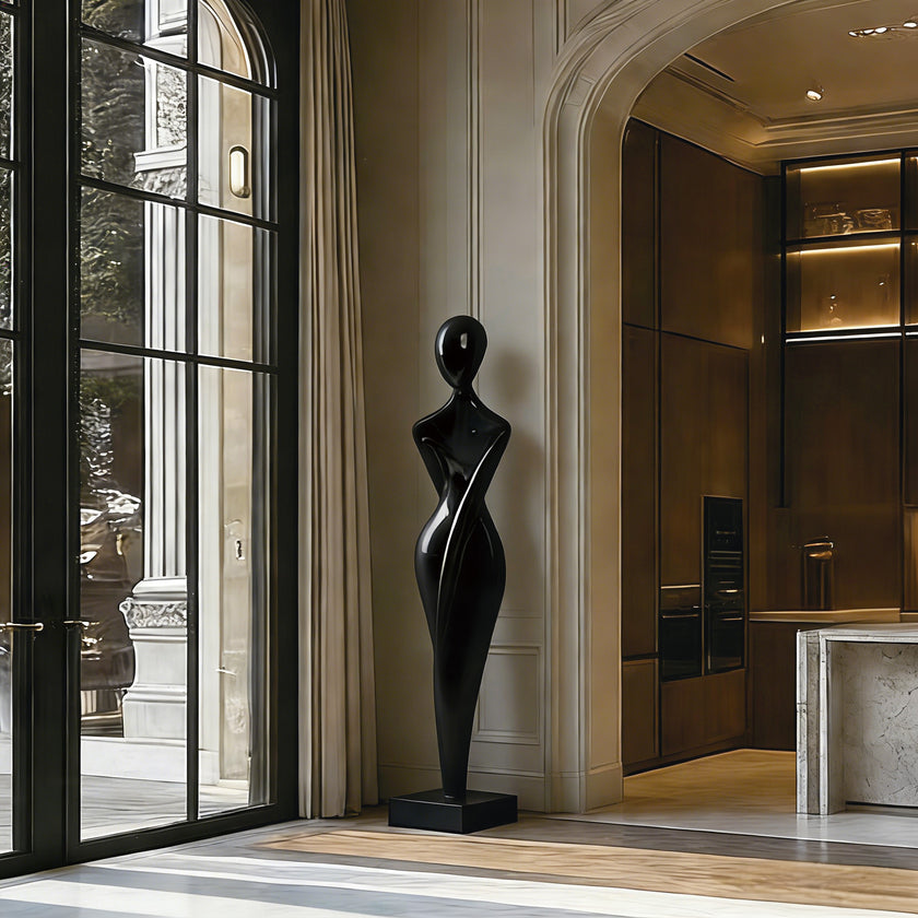 Graceful Female Silhouette Glossy Black Bronze Sculpture stands on a matching base in a modern interior hallway with arched entryways, warm wood cabinetry, and large windows.