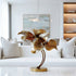 Graceful Lily Leaves Metal Art Home Decor Bronze Statues with textured, layered petals on a curved stem and round base, displayed on a white table in a modern living room setting.