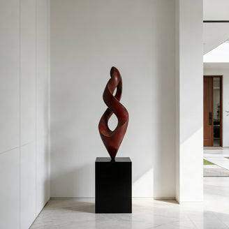 Twisting Red Bronze Flame Floor Sculpture Abstract Art Sculptures of two intertwined spiral forms in a glossy dark reddish-brown finish, mounted on a black rectangular pedestal, set against a minimalist white interior wall.