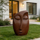 Serene Meditative Face Abstract Bronze Sculpture of a stylized face sits on a green lawn in front of a modern house with white walls and black-framed windows.