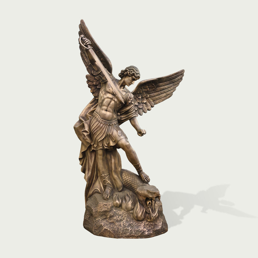 Holy Defender Classical Archangel St. Michael Bronze Sculpture standing on a rocky base and defeating a serpent, photographed against a plain light gray background with a soft shadow cast to the right.
