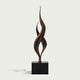 Dual Weave Abstract Bronze Sculpture  with two flowing spiral forms rising from a black rectangular base, photographed against a light warm gray background.