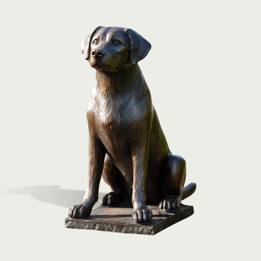 Realistic bronze Labrador dog statue in a calm seated pose, featuring floppy ears, an attentive facial expression, carefully sculpted fur texture, sturdy paws, and a rectangular base with a dark aged bronze patina.