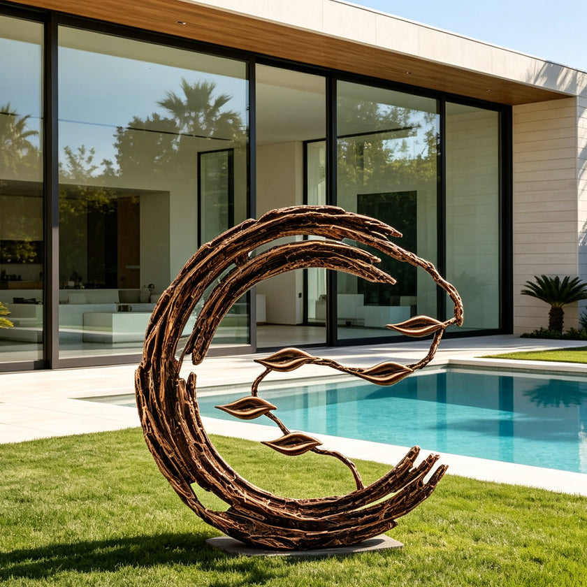 Large abstract bronze crescent sculpture displayed on a manicured lawn beside a modern swimming pool, featuring layered branch-like curves, flowing organic lines, and suspended leaf forms against a contemporary villa.