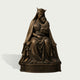 Front view of a crowned Madonna and Child bronze sculpture featuring the seated Virgin Mary holding the infant Jesus, finely modeled faces and hands, deeply folded robes, and an ornate floral base with fleur-de-lis detail.