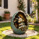 Whimsical bronze bunny sculpture nestled inside a cracked egg, displayed in a sunny residential garden, featuring a sleeping rabbit with folded paws, oversized feet, smiling expression, turquoise verdigris patina, and warm bronze highlights.