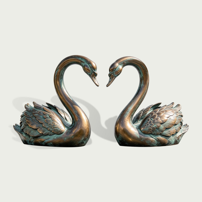 Bronze sculpture of two graceful swans facing each other with their long curved necks forming a heart, featuring finely sculpted layered wings, warm bronze tones, and subtle green patina details.