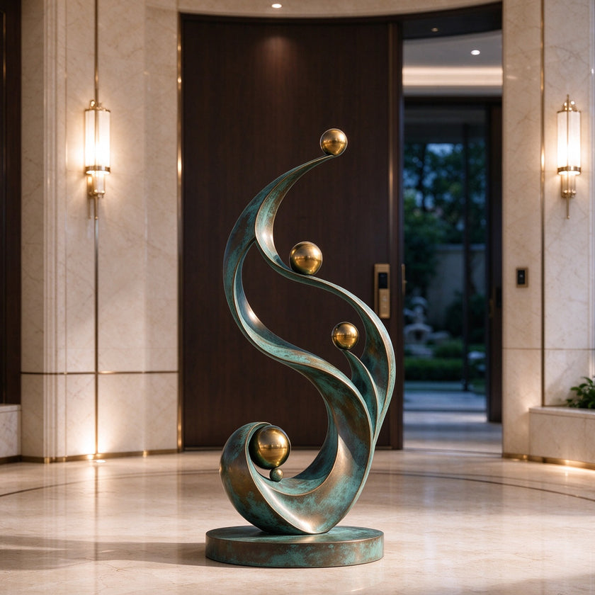 Abstract bronze sculpture displayed in a luxury interior, featuring sweeping verdigris patina curves and polished golden spheres arranged in a graceful vertical composition.