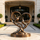 Large bronze dove sculpture displayed at a luxury residence entrance, featuring two birds, an olive branch, and flowing heart-shaped curves on a round bronze base.