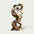 Front product view of an artistic bronze sculpture featuring a gracefully raised hand beneath a large open heart with a smaller suspended heart, decorative leaves along one side, and intertwined ribbon-like curves forming another heart near the base, finished in warm antique bronze with golden highlights.