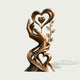 Front product view of an artistic bronze sculpture featuring a gracefully raised hand beneath a large open heart with a smaller suspended heart, decorative leaves along one side, and intertwined ribbon-like curves forming another heart near the base, finished in warm antique bronze with golden highlights.
