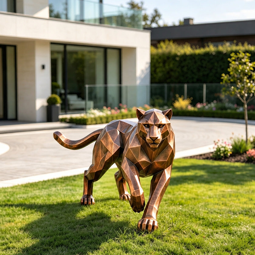 A geometric bronze sculpture of a prowling panther with a faceted low-poly design. This sleek, modern metal art piece features a stealthy walking posture, displayed on a sunny green lawn outside a contemporary villa.
