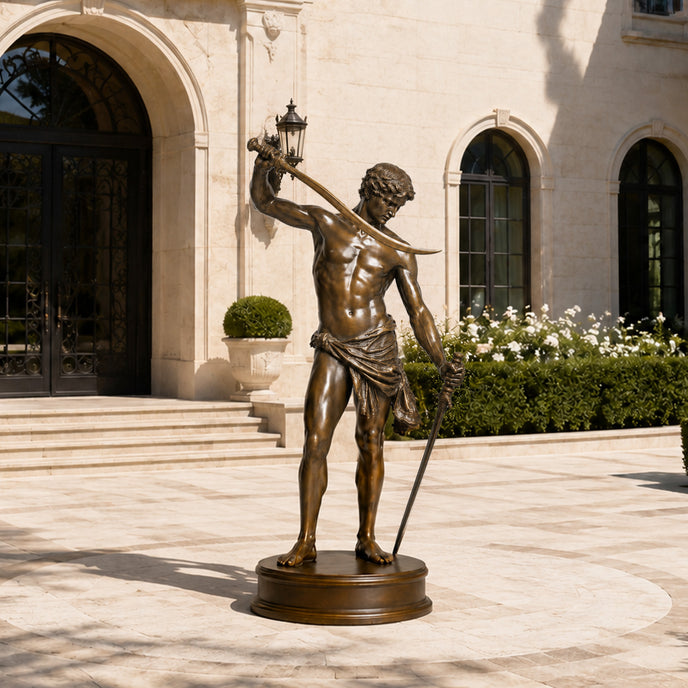 A life-size bronze sculpture of a muscular classical warrior holding a curved sword. This highly detailed ancient metal art features draped fabric around the waist, displayed outdoors on a stone courtyard outside a luxury grand estate.
