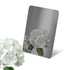 Stainless steel color sample mirror polished black sheet with a reflection of white flower on a white background