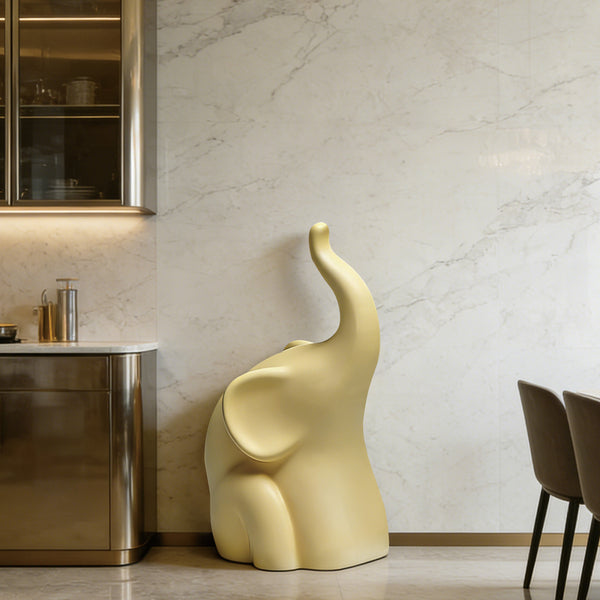 Modern Abstract Elephant Sculpture with Raised Trunk in a modern interior setting with marble walls and metallic furniture.