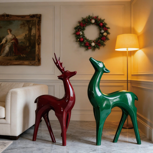 Vibrant Fiberglass Sculpture Christmas Reindeer Pair For Modern Decor. Two decorative deer statues, one red and one green, in a living room setting with a wreath on the wall.