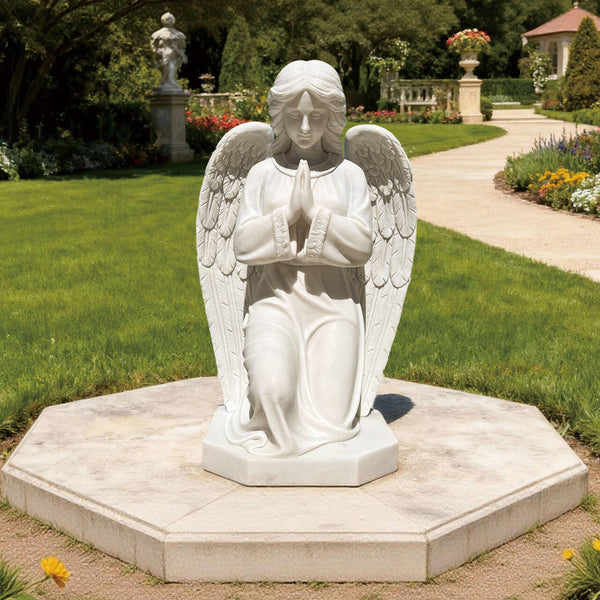 knneling praying angel marble statue in a garden setting with greenery and flowers.