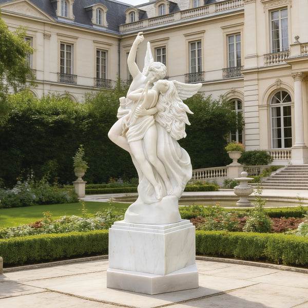 Romantic cupid and psyche marble statue replica in a garden with a classical building in the background