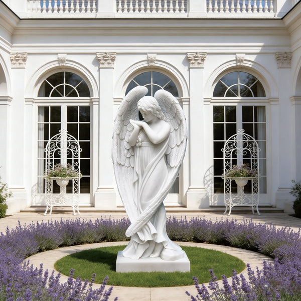 Elegant stainding praying marble angel statue in front of a white building with arched windows and lavender flowers