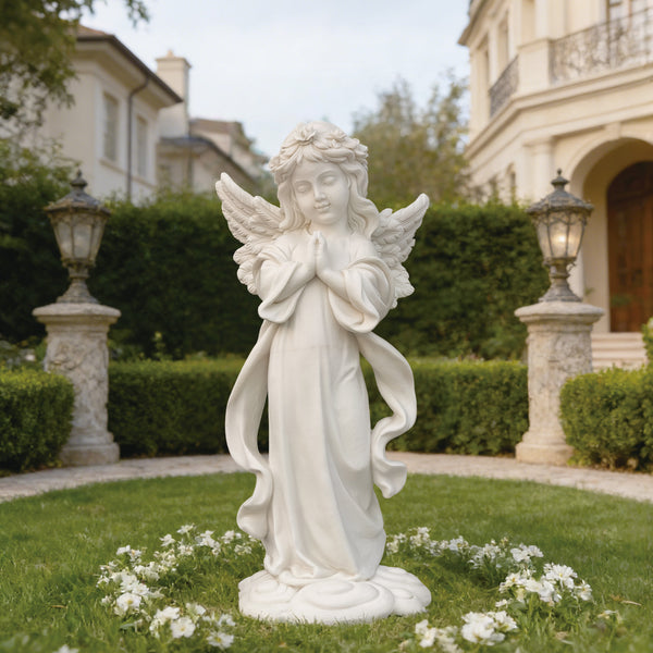 Standing Praying Child Angel Marble Statue  in a garden setting with a house in the background