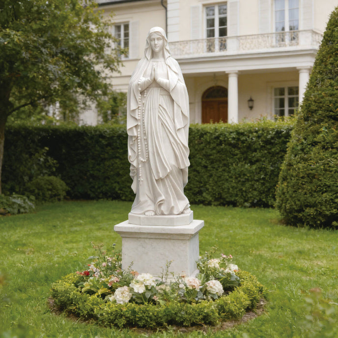 Graceful Our Lady of the Rosary Marble Statue  in a garden setting with flowers and a building in the background