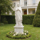 Graceful Our Lady of the Rosary Marble Statue  in a garden setting with flowers and a building in the background