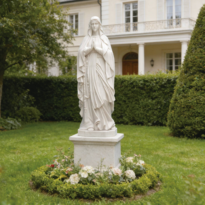 Graceful Our Lady of the Rosary Marble Statue  in a garden setting with flowers and a building in the background