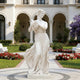 Elegant Autumnal Harvest Marble Statue With Grapes in Luxury Hotel with flowers surroundings. 
