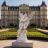 Mythological Love Cupid and Psyche Marble Statue in front of a grand building with a blue sky.
